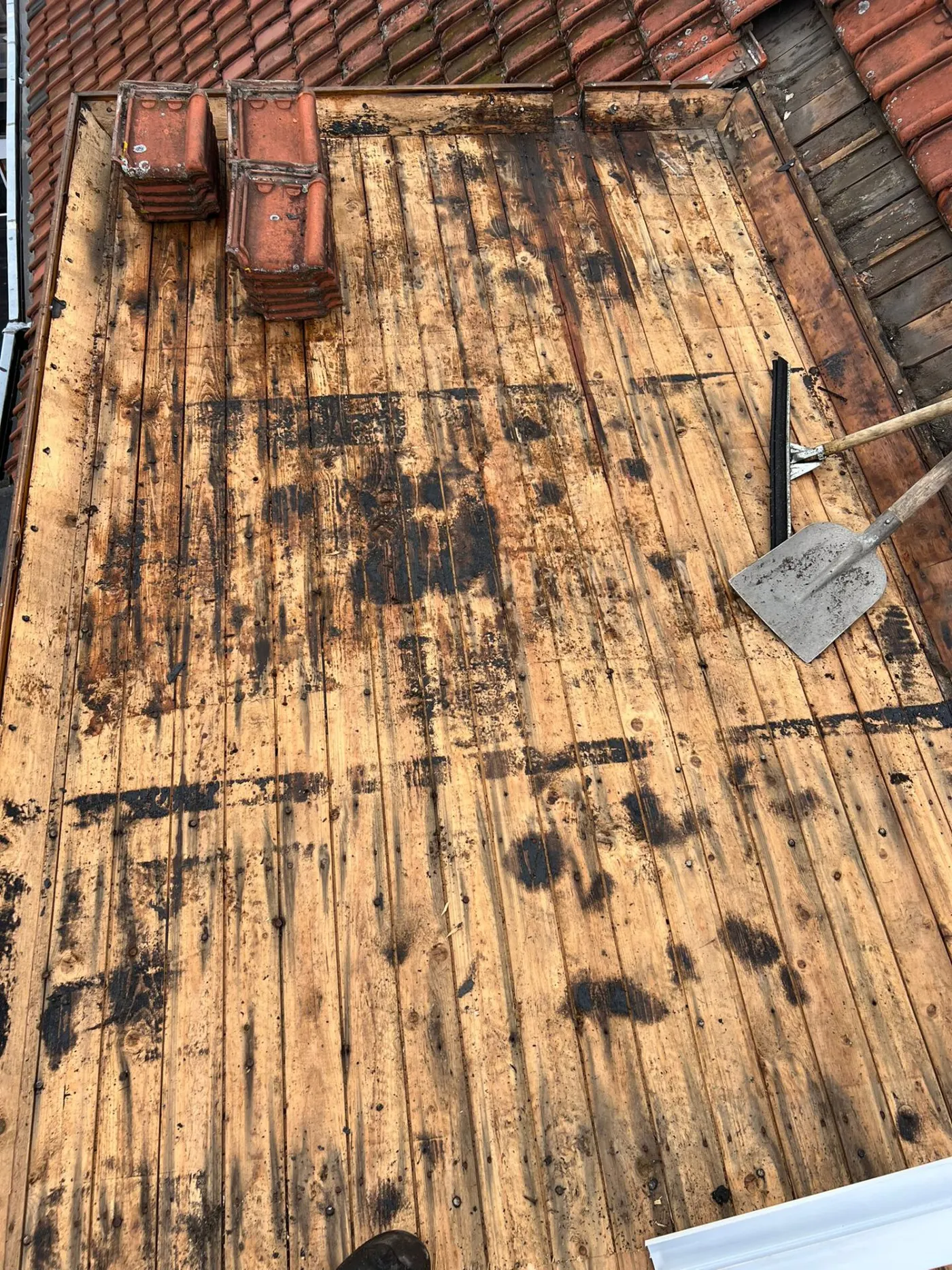 Rot dakbeschot onder een oud dak, blootgelegd tijdens een lekkagereparatie