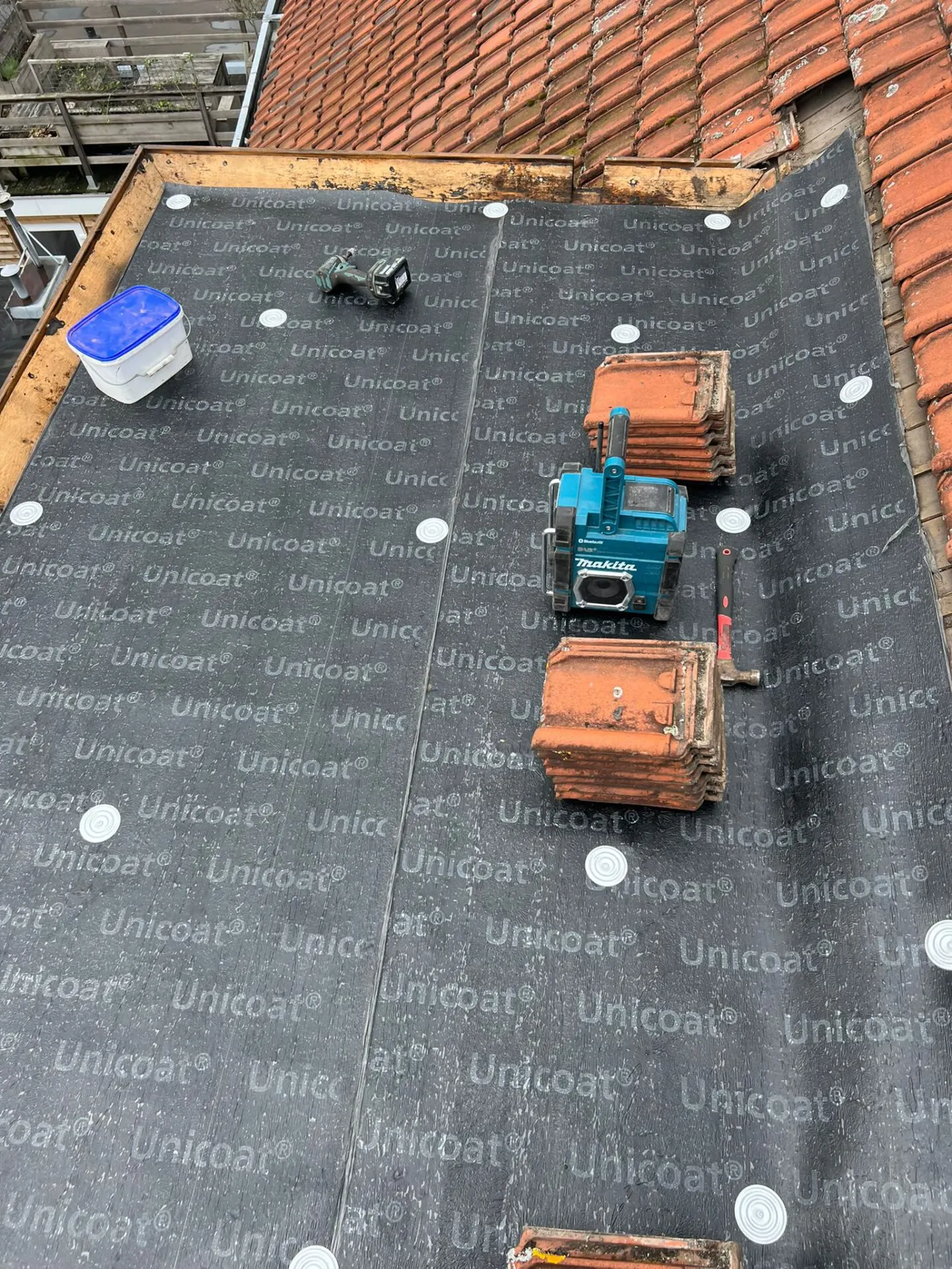 Nieuwe onderlaag en gereedschap op een plat dak tijdens herstel