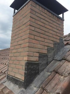 Schoorsteen met nieuw loodwerk op een pannendak