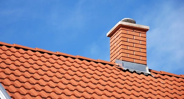 Gemetselde schoorsteen op een oranje pannendak