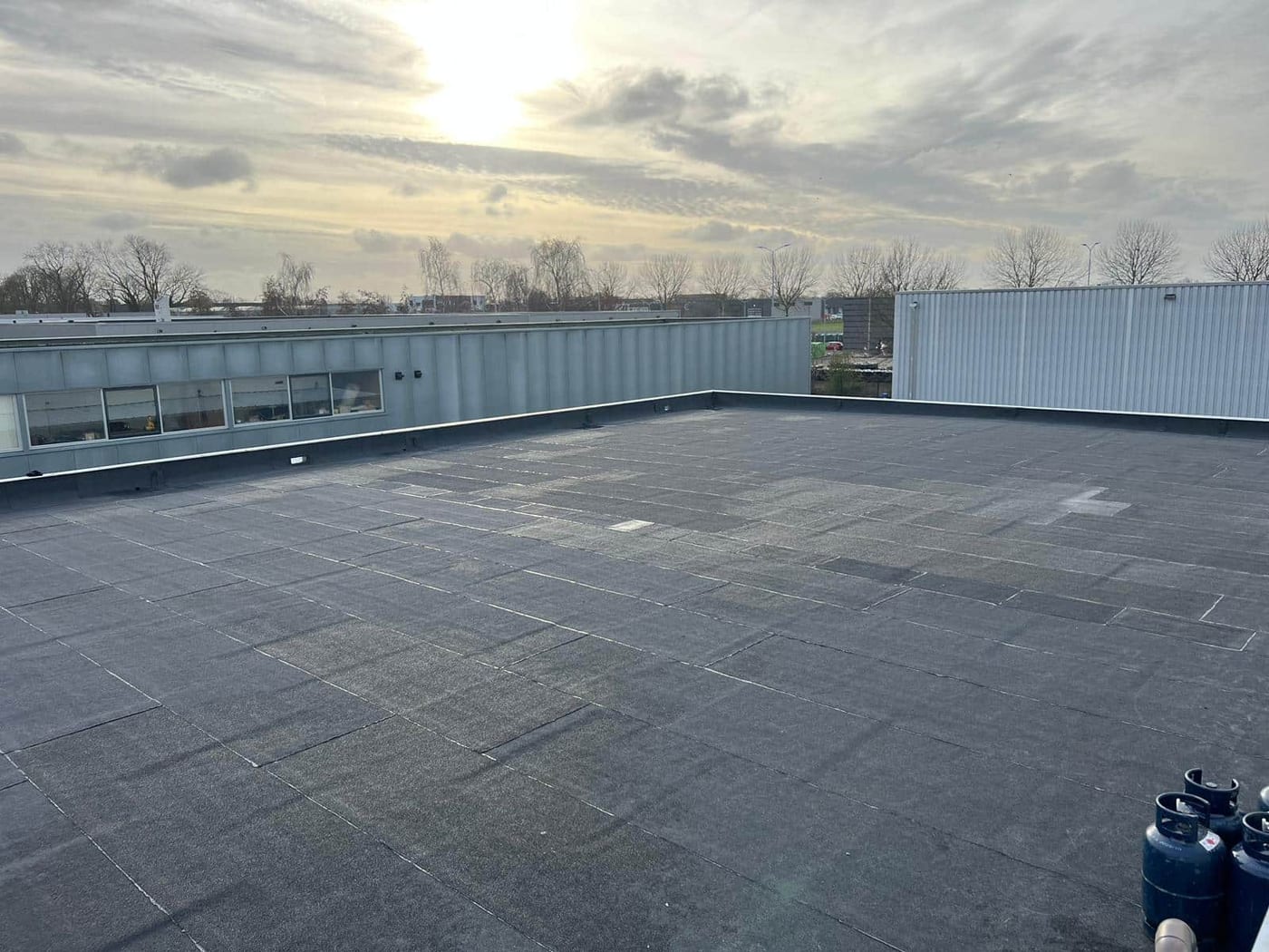 Plat dak met bitumen dakbedekking bij zonsondergang
