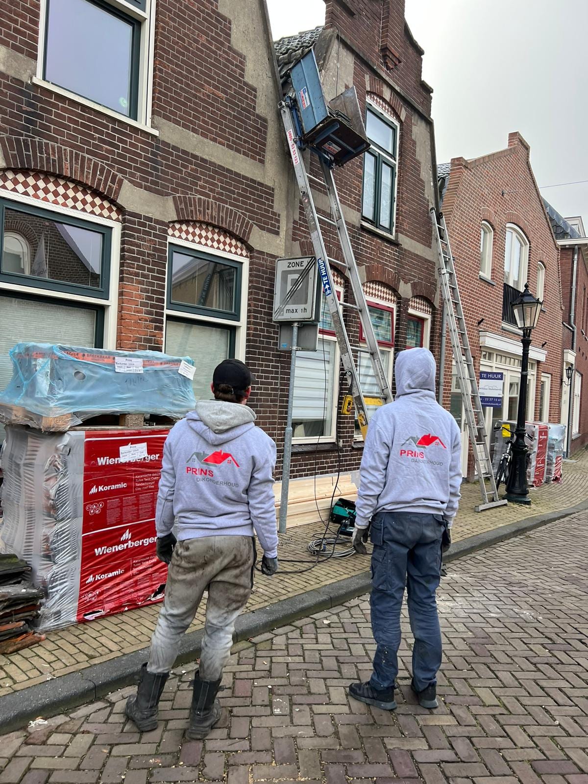 Twee dakdekkers van Prins Dakonderhoud met materiaal bij een woning